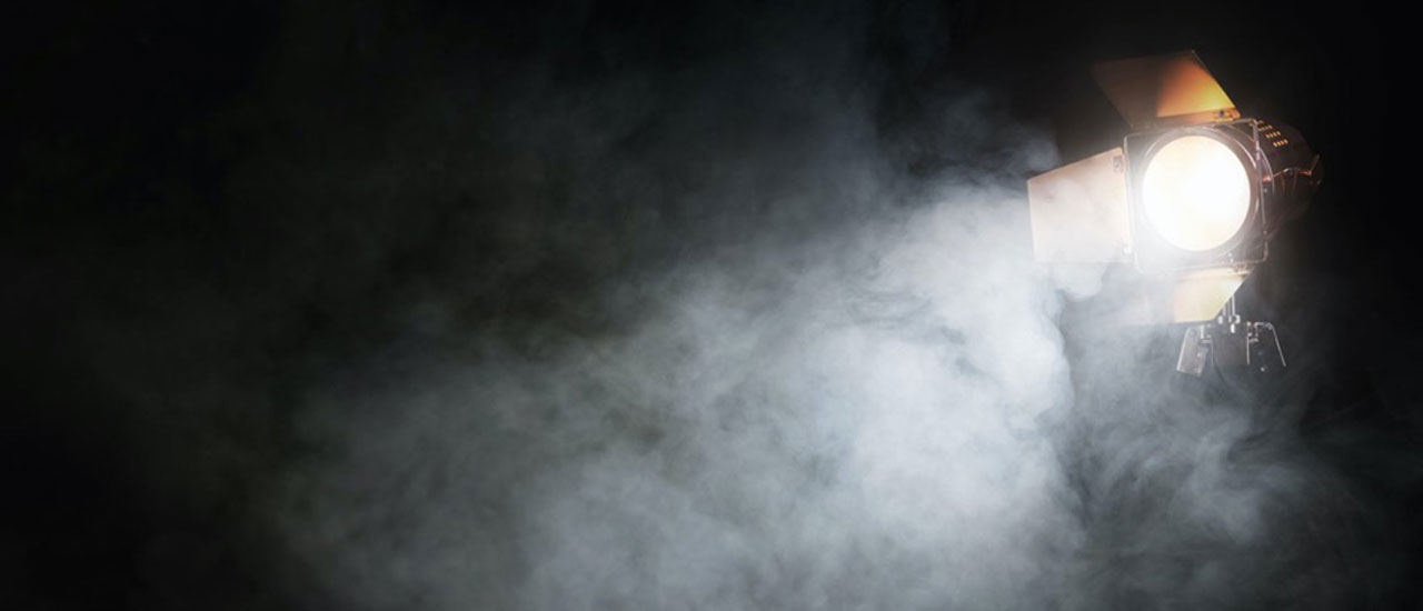 A stage light shining in the darkness, surrounded by fog