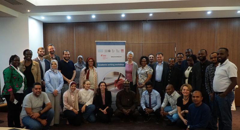 Workshop attendees standing for photo infront of workshop banner in conference room.