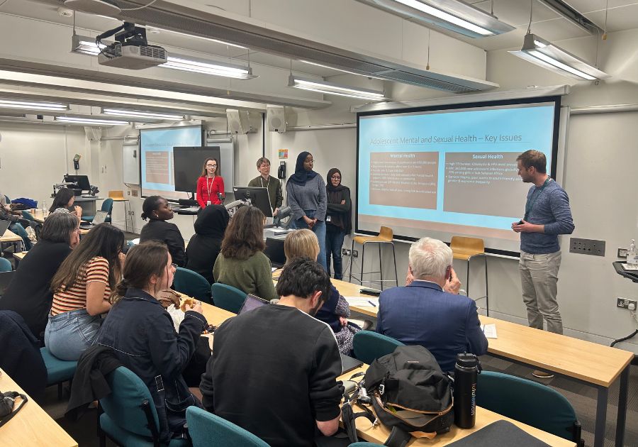 Group of five people from the Hackathon presenting in front of an audience.