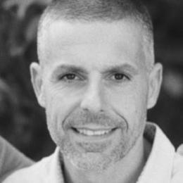 Black and white image of a white man with short hair smiling