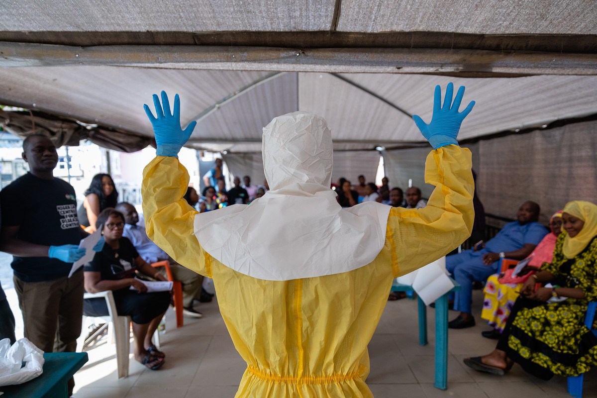Dr Abdulmajid Suleiman Musa shows a group of Nigeria Centre for Disease Control staff how a correctly prepared PPE suit should look when working in a virus hit region, Keffi, Nasarawa stat, Nigeria 2019. Credit: Louis Leeson for LSHTM / UK Public Health Rapid Support Team.