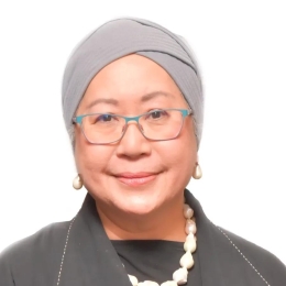 Woman with grey headscarf and glasses smiling at the camera