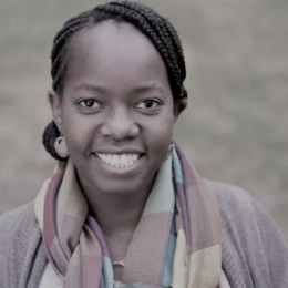 Black woman with black hair and a pink scarf smiling