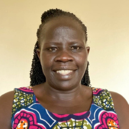 Black woman with braided hair and colourful dress smiling