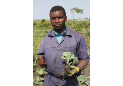 Disabled farmer, Moza holding a crop from his farm. Photo credit: Carlos Litulo