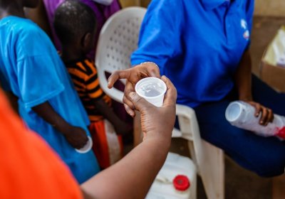  	A patient is given a does of IV and DP as part of a mass drug administration trial attempting to eradicate malaria in the region. IV (Ivemectin) kills any mosquito as it bites the patient, and the DP (Dihydroartemisinin-Piperaquine) kills the malaria parasite. Basse, The Gambia. Credit: Louis Leeson/LSHTM 