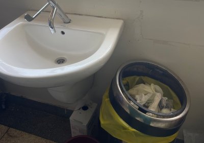 A sink in a healthcare setting with improvised soap containers and a waste bin. Credit: Lauren Hookham