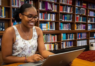 LSHTM student in library working on laptop